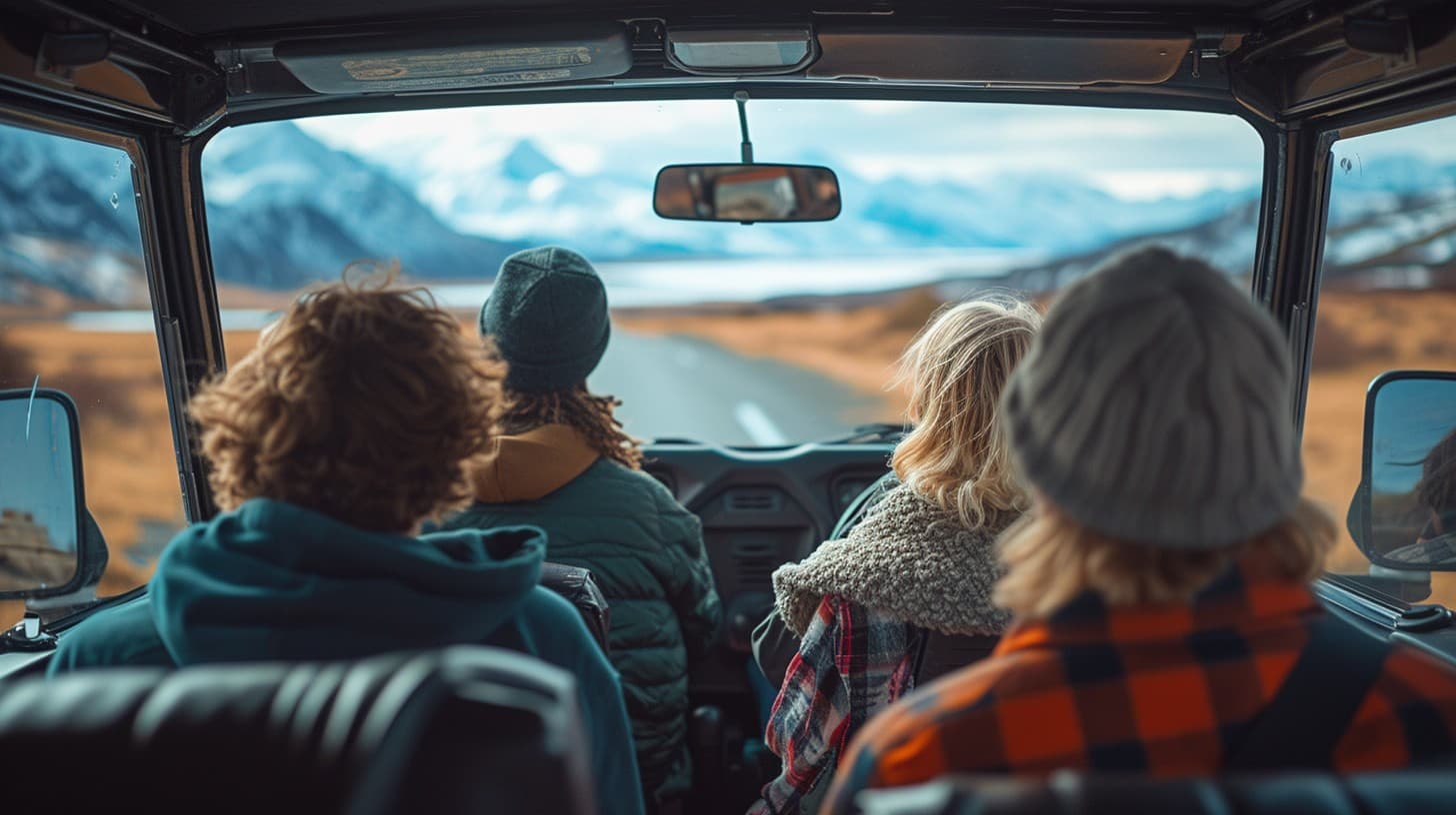 Four people in a car looking out at a snow-covered mountain range